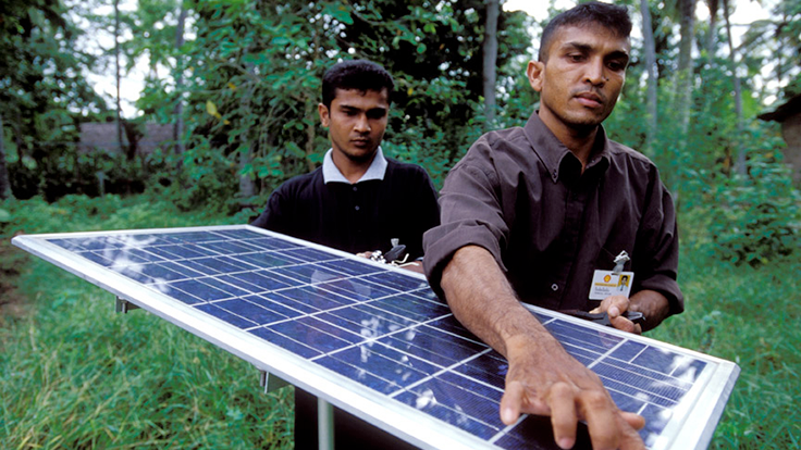 Two people carrying a solar panel in Sri Lanka.